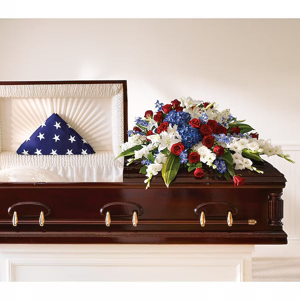 Casket with American flag and floral arrangement in a funeral setting