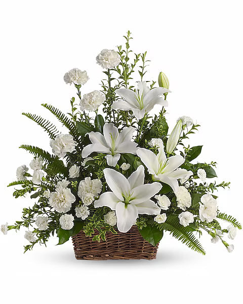 White lilies and leafy greens elegantly arranged in wicker basket on white backdro