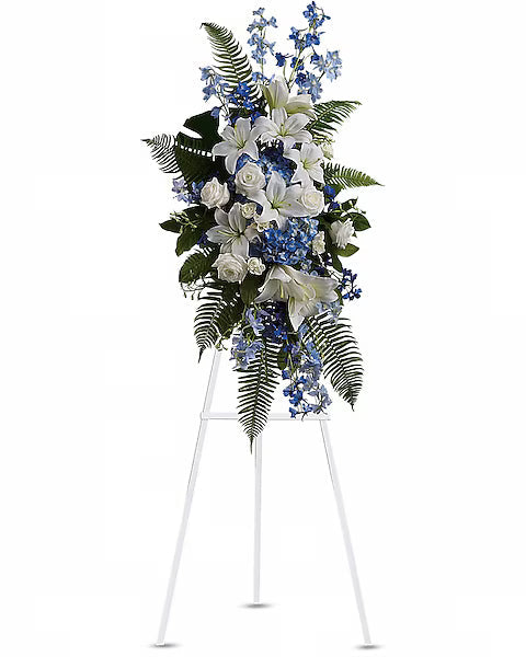 White, blue, and green flowers beautifully arranged on white stand