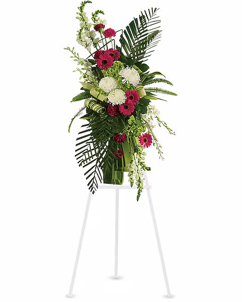 Floral arrangement of mutlicolor with grean leaves on a white stand