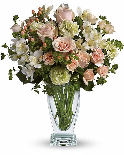 Bouquet of pink and white flowers with green leaves in a clear glass vase 