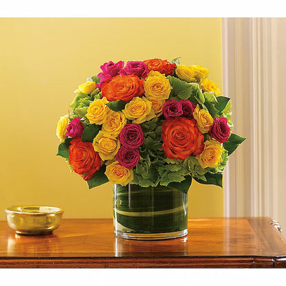 Vibrant flowers in a clear vase against a yellow wall.