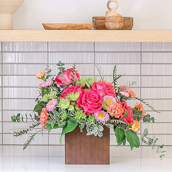 Bright flowers in wooden box on counter